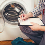 Repairman is repairing a washing machine on the white background