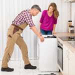 Worker Repairing Washing Machine In Kitchen