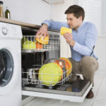 Man Arranging Dishes In Dishwasher