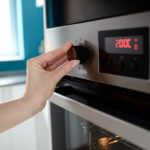 Close up of woman’s hand setting temperature control on oven