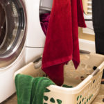 Domestic Life:  Woman removing towels from clothes dryer.  Laundry basket