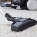 Long end of vacuum cleaner cleaning thick, white carpet