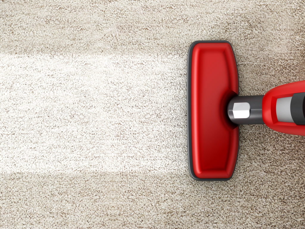 Red vacuum cleaner cleaning a carpet.