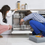 Woman Looking At Repairman Repairing Dishwasher