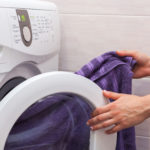 Woman loading laundry to the washing machine