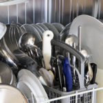 Close-up of a dishwasher with cleaned dishes and utensils inside