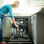 Pretty blonde woman emptying the dishwasher