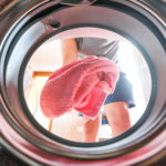 Young man doing laundry view from the inside of washing machine