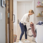 Mature woman loading clothes in washing machine